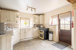 a kitchen with wooden cabinets and a black refrigerator at Cotswold Thatched Cottage in Mickleton