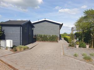 a black and gray building with a brick driveway at Chalet 36 in Giethoorn