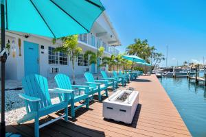 una fila de sillas y sombrillas en un muelle junto al agua en Latitude 26 Waterfront Boutique Resort - Fort Myers Beach en Fort Myers Beach