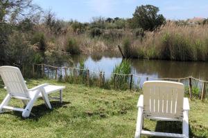 Réf LS 55 : Cabane de Gardian 6 pers في سانت ماري دو لا مير: كرسيان بيض يجلسون في العشب بالقرب من النهر