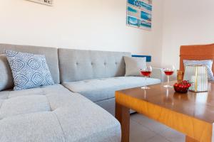 sala de estar con sofá y mesa con copas de vino en Molí del Mar en L'Escala