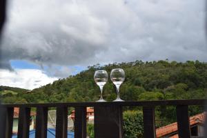 Dois copos de vinho em cima de uma varanda em Chale Ideal em Conceição da Ibitipoca