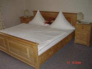 a wooden bed with white sheets and pillows on it at Ferienwohnung Haus Bergrast in Berchtesgaden