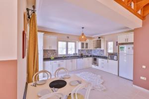 a kitchen with white cabinets and a table and chairs at Villa Günbatımı in Kaş