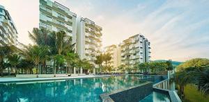 a large swimming pool with palm trees and buildings at By the sea Duplex penthouse baby in Batu Ferringhi