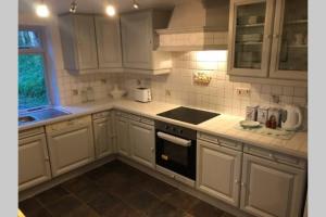 a kitchen with white cabinets and a stove top oven at Historic 17th century farmhouse in Wales in Gwernymynydd +22 photos