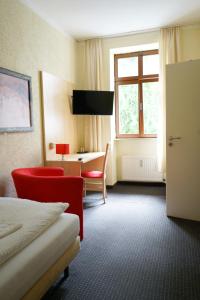 ein Hotelzimmer mit einem Bett, einem Schreibtisch und einem Fenster in der Unterkunft Gästehaus Lisakowski Pension am Brautwiesenpark in Görlitz