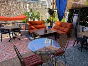 a patio with tables and chairs and a glass table at Coco Marco Hôtel in Nyons