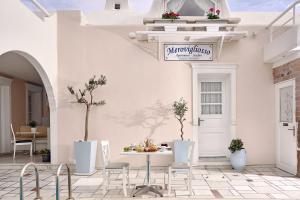 a white patio with a table and chairs at Merovigliosso in Imerovigli