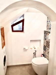 La salle de bains blanche est pourvue de toilettes et d'une fenêtre. dans l'établissement La Maison Blanche, à Iglesias