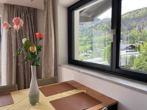 Modern Living Sankt Gilgen في سانكت جيلجن: مزهرية مع الزهور على طاولة أمام النافذة