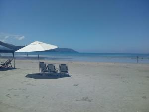 two chairs and an umbrella on a beach at Confortável Apto.Com Piscina para 8 pessoas-Ubatuba-Enseada in Ubatuba
