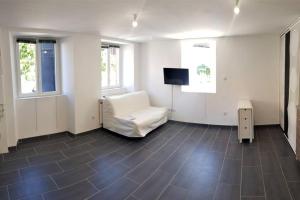 a living room with a white chair and a flat screen tv at Studio neuf 001 proche gare TGV, A36 et Hôpital in Botans