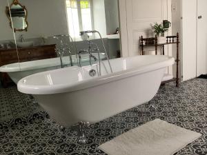 a white bath tub in a bathroom with a sink and a bath tub at Chambre baroque in Hagenthal-le-Bas