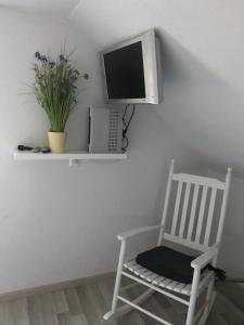 a white rocking chair with a television on a wall at Idyllische kleine Ferienwohnung in Obdach