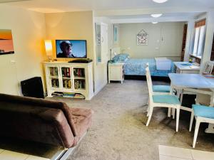 um quarto com uma cama e uma sala de estar com um sofá em Whitby Studio - Mairangi Bay Beach em Auckland