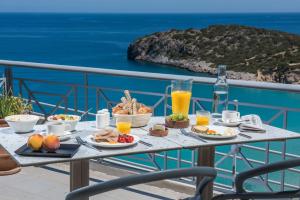 einen Tisch mit Speisen und Getränken auf einem Balkon mit Meerblick in der Unterkunft Mistral Mare Hotel in Istro