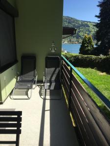 2 sedie su un portico con vista sull'acqua di Rosebeach Appartement am Ossiachersee und Gerlitzen Skipiste a Bodensdorf