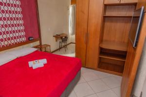 Schlafzimmer mit einem Bett mit einer roten Decke und einem Holzschrank in der Unterkunft Pousada Ondas do Forte in Cabo Frio