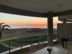 a balcony with a table and chairs and a sunset at Ballito Manor - Manor Gardens 204 - complex generator in Ballito