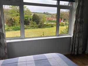 a bedroom with a window with a view of a field at SunnyVale Valley View Cottage in Gorran Haven
