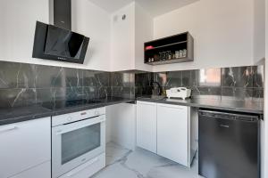 cocina con armarios blancos y TV en la pared en Art apartament en Gdansk