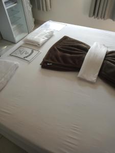 uma cama branca com duas almofadas em cima em JOVI Pouso & Café em Capitólio