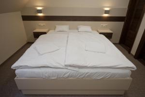 a large white bed with white sheets and pillows at Napkelte Panzió in Napkor