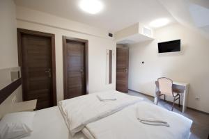 a white bedroom with two beds and a chair at Napkelte Panzió in Napkor