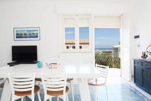 uma sala de jantar branca com uma mesa e cadeiras brancas em BeachSide Rooms & Suites em San Vito lo Capo