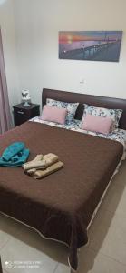 a large bed with brown sheets and pink pillows at Fotini's Apartment in Nea Peramos