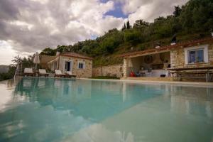 a large swimming pool in front of a house at Astrali Stone Villas in Paramythia