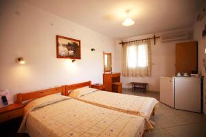 1 dormitorio con 2 camas y nevera en Alexandros Rooms & Studios, en Skopelos Town