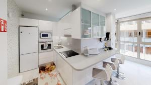 a kitchen with white cabinets and a counter with chairs at Marina Suite in Santa Cruz de Tenerife