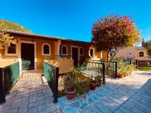 a fence in front of a house with a tree at Afrodite's Pool and Studios in Paleokastritsa