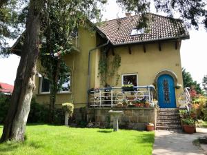 een geel huis met een blauwe deur en een tuin bij Lovely Nest near Budapest in Dunakeszi