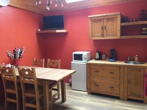 a kitchen with red walls and a wooden table at Lac d'Annecy in Doussard