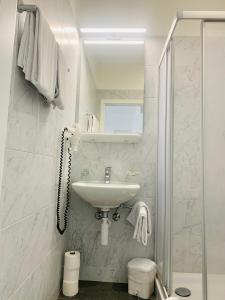 a white bathroom with a sink and a shower at Hotel Gamper in Bellinzona