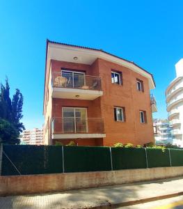 a brick building with a fence in front of it at Kesito Family Apartments in Lloret de Mar