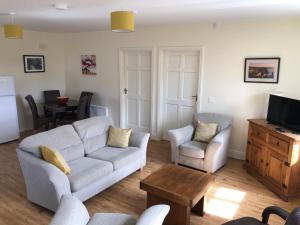 a living room with a couch and chairs and a tv at Clairhouse Accommodation in Lahinch