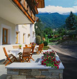 eine Terrasse mit einem Tisch, Stühlen und Blumen in der Unterkunft Gasthof Weisses Kreuz in Naturns