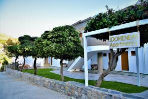 una señal de bienvenida frente a un edificio con árboles en Idomeneas Apartments, en Sougia