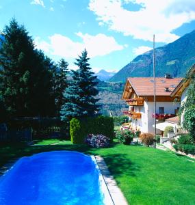 a swimming pool in a yard with a house at Gasthof Weisses Kreuz in Naturno