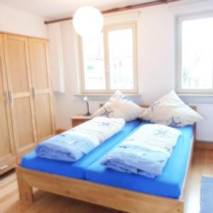 Bett mit blauer Bettwäsche und Kissen in einem Zimmer in der Unterkunft Doris` Hus in Travemünde