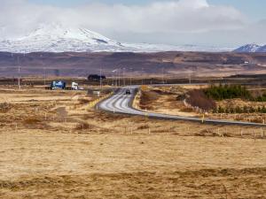 a road with a snow covered mountain in the background at Guesthouse Bitra B&B in Selfoss