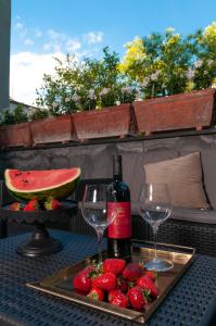 uma mesa com dois copos e uma garrafa de vinho e morangos em Casa Teresinella Garden em Torre Annunziata