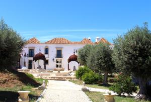 una casa blanca con árboles delante de ella en Hotel de Charme Capela das Artes, en Armação de Pêra