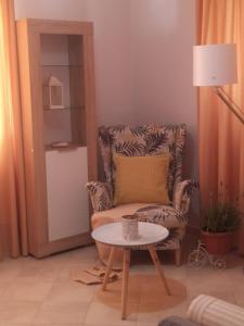 uma sala de estar com uma cadeira e uma mesa em Roza's Home and Studios em Benitses