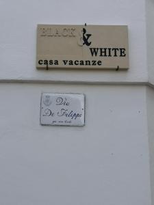 una señal en un lado de un edificio blanco en Black & White, en Matino