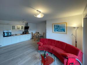 a living room with a red couch and a kitchen at Ferienwohnung König Ludwig XIV in Saarlouis